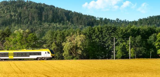 Train in motion across agricultural fields and forests.